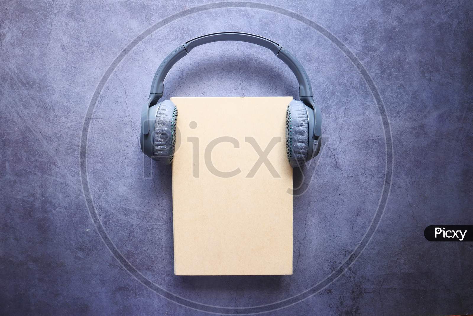 Audio Book Concept. Headphones And Book Over Wooden Table.