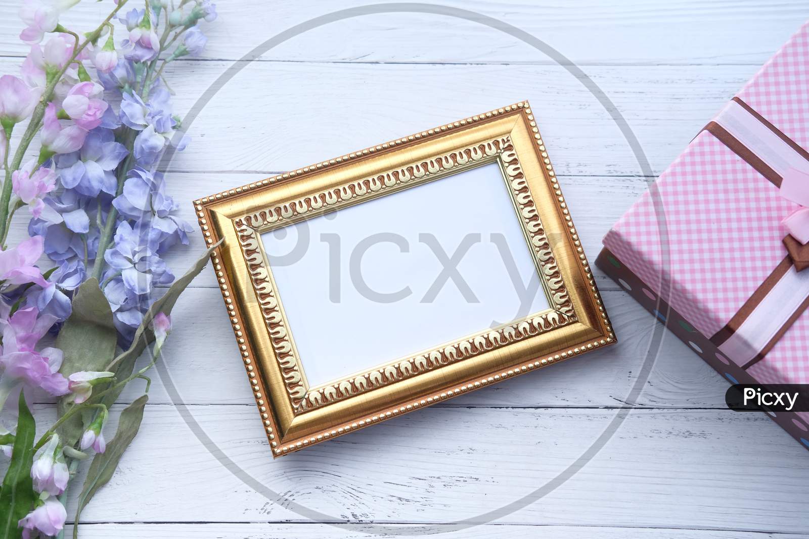 Empty Picture Frame, Gift Box And Flower On Table.