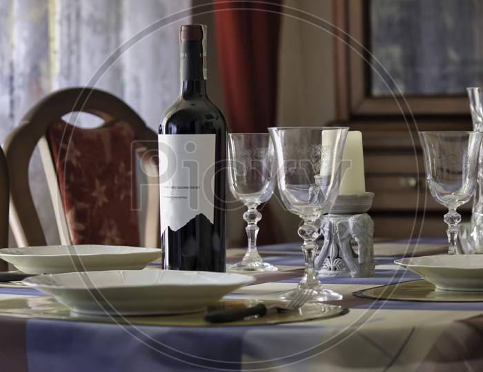 Wine Bottle, Glass And Plates On A Dining Table Before A Family Holiday Feast