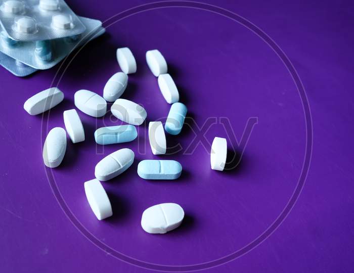 Close Up Of Pills Spilling On Purple Desk