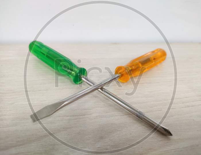 Screw Driver pair of flat head minus and plus on light Textured background.