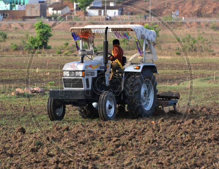 TIKAMGARH, MADHYA PRADESH, INDIA - JUNE 15, 2020: Indian farmer with tractor preparing land for sowing with harrow.