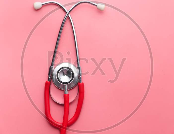 High Angle View Of Red Stethoscope On Pink Background.