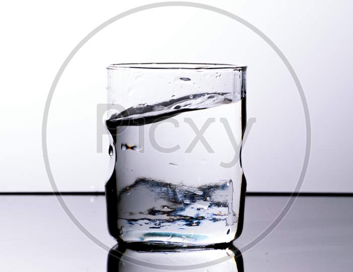 Water In A Glass With Curved Upper Surface After A Splash. White Background