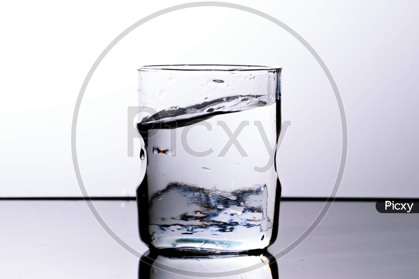 Water In A Glass With Curved Upper Surface After A Splash. White Background