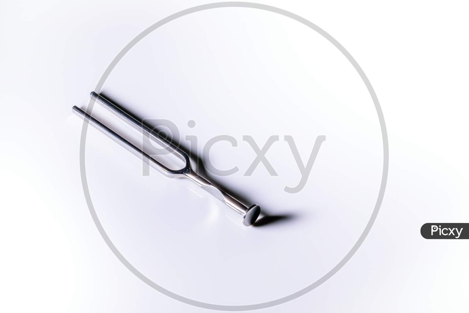 An Isolated Metallic Tuning Fork In A White Background With Space For Text