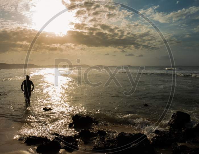 Sunset At The Edge Of The Sea. Silhouette Of A Man Looking At The Sun.