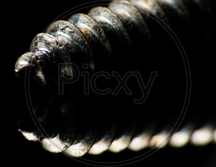 An Isolated Screw Placed On A Reflective Surface With A Dark Background. Selective Focusing