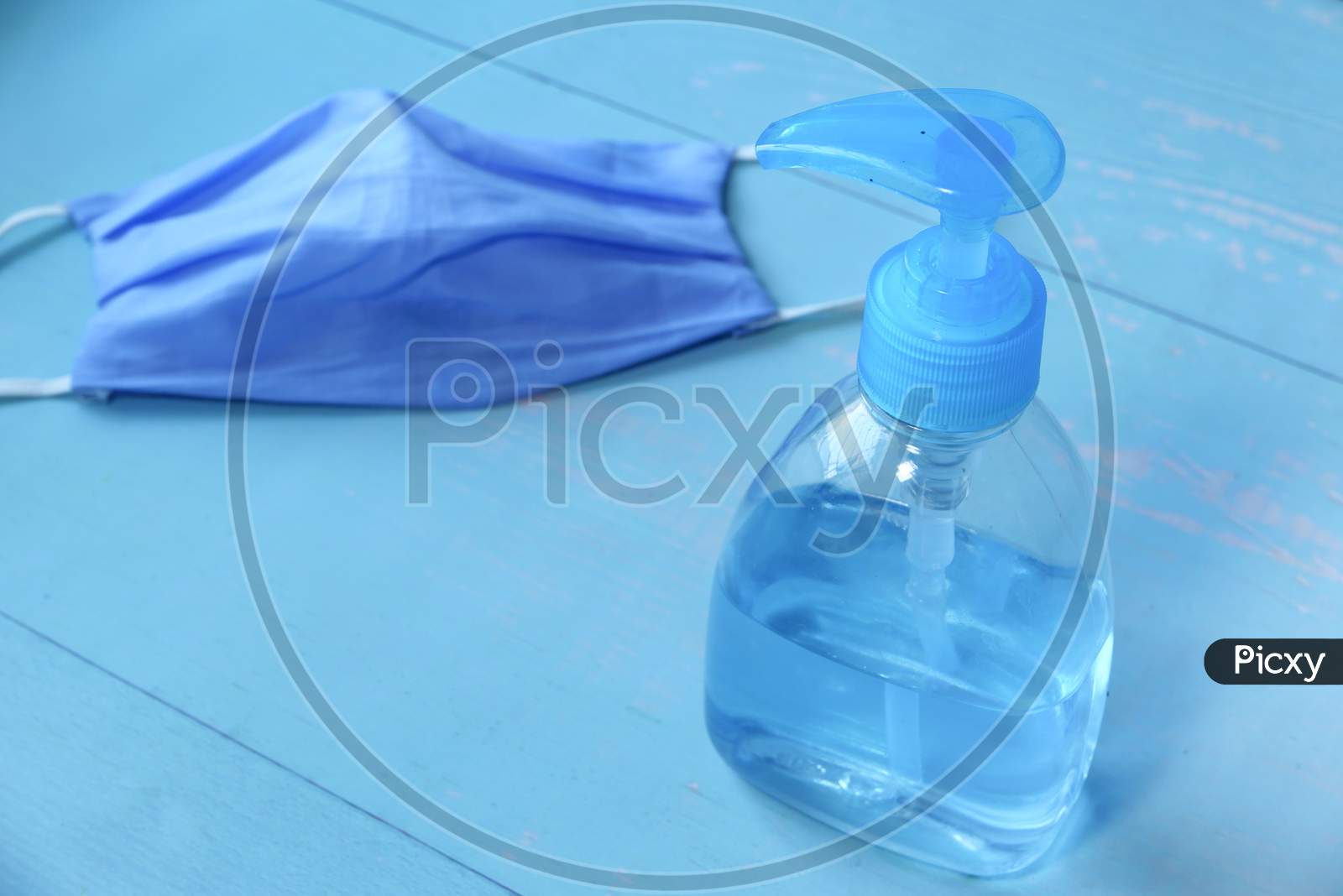 Face Mask, Sanitizer On Wooden Table With Copy Space