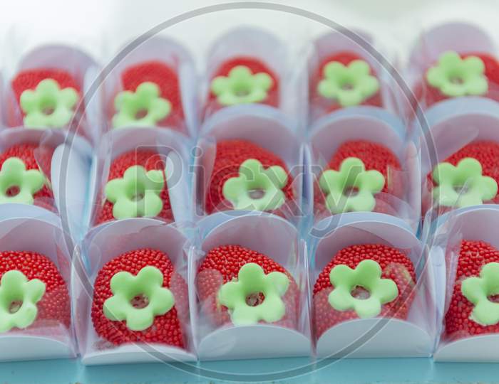 Red Sprinkled Candies In White Paper Box On Blue Tray With Shallow Depth Of Field.