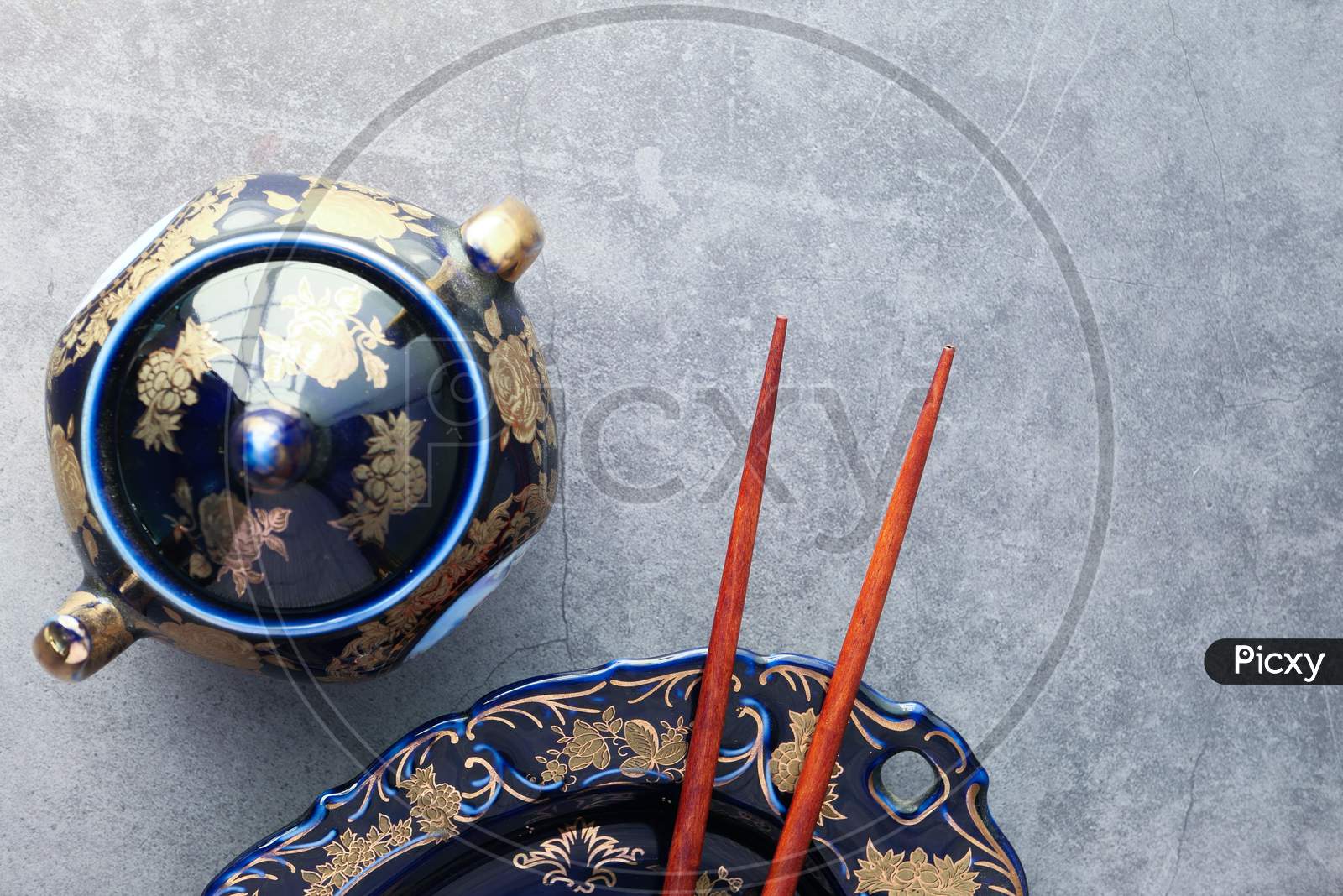 Empty Plate, Teapot With Herbal Tea And Chopsticks Over Table