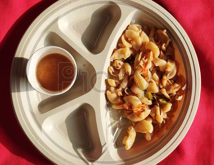 Cooked Macaroni with elbow pasta  an cheese with tea and tomato sauce indian breakfast on red background