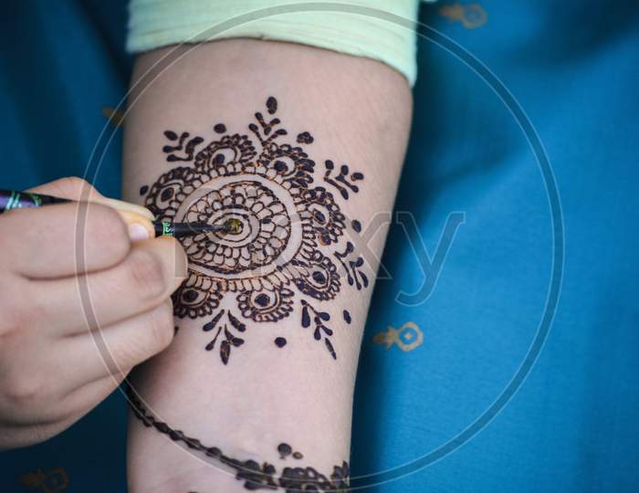 Mehndi Artist making mehndi design on the Indian bridal hand. Mehndi is traditional Indian decorative art.