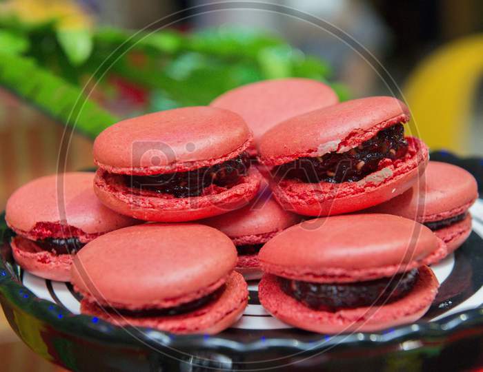 Several Pink Macaroons On A White And Black Ceramic Tray.