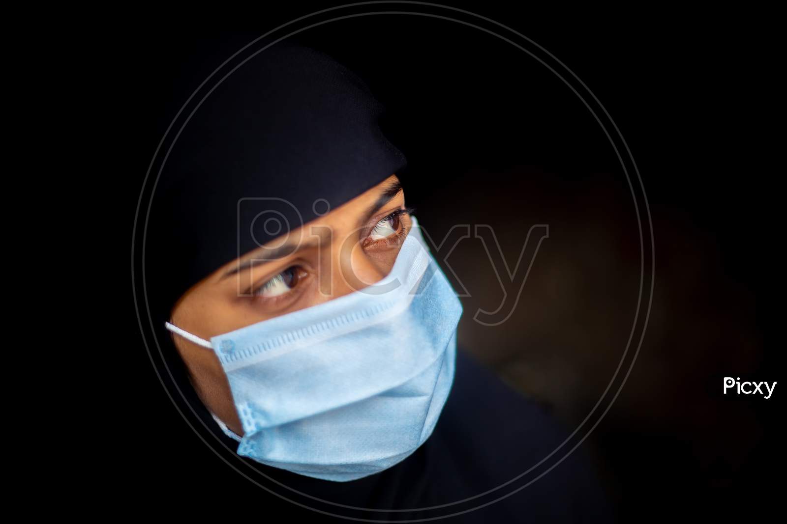 An Asian Muslim Girl Wearing A Surgical Mask For Coronavirus Protection. Black Hijab Woman Wearing A Blue Mask For Safety. Side Views.