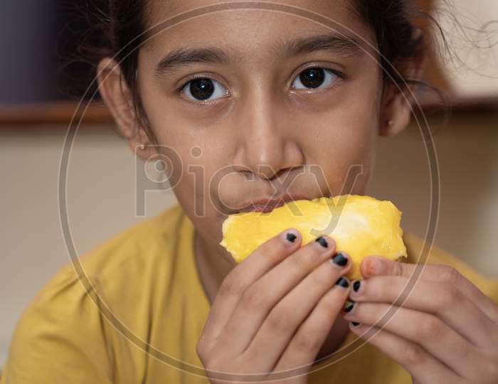 jaipur . Rajasthan . India - June 12, 2020. Happy little girl eating mango (lockdown activities)
