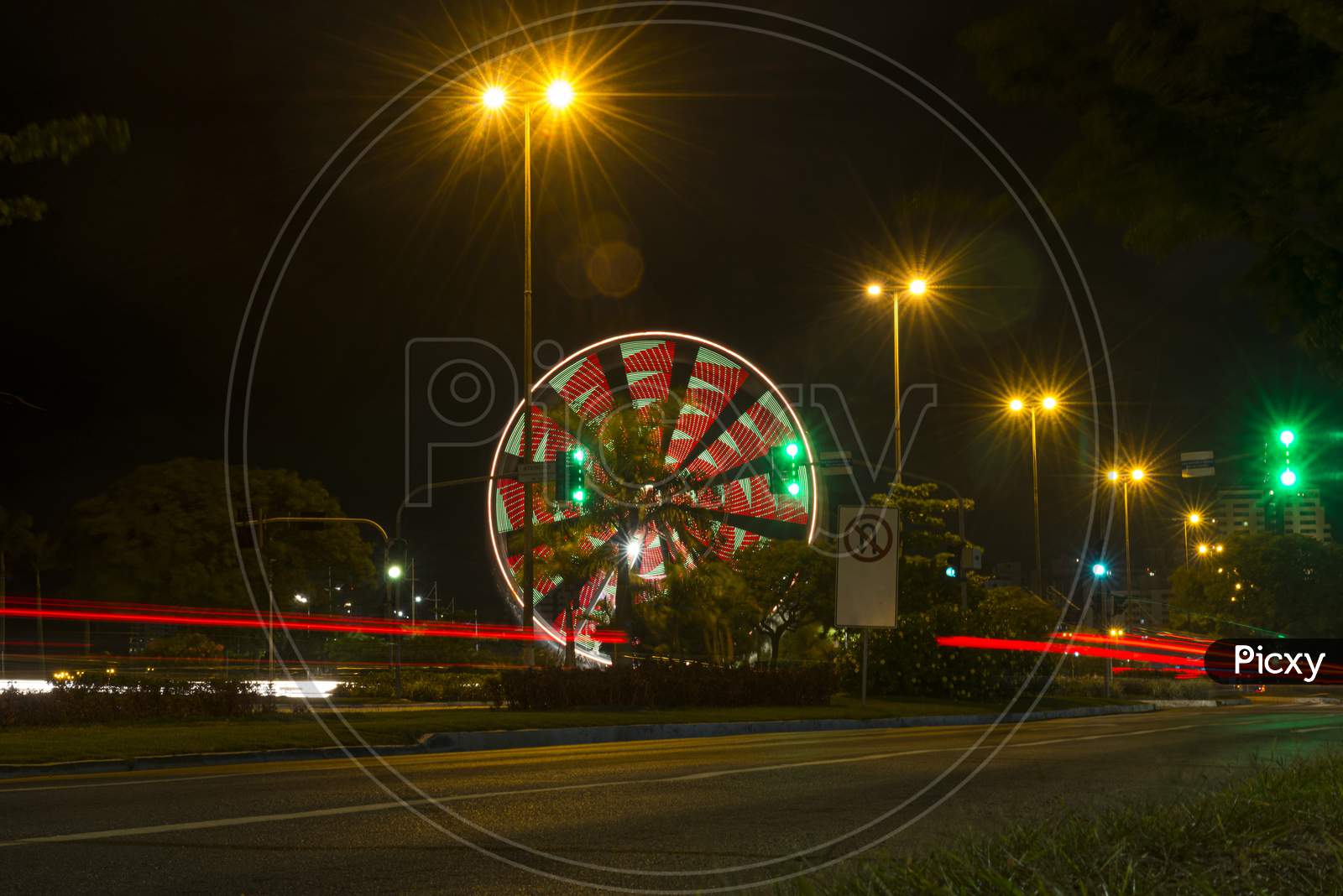 Long Exposure Of Colorful Ferris Wheel And Light Trails On The Expressway Road At Night.