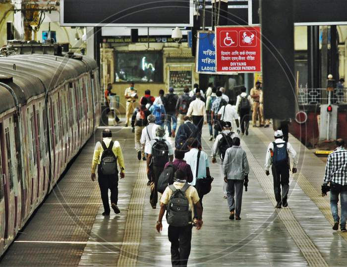 Passengers walk on a platform as they arrive with a train scheduled for essential service workers after the government eased a nationwide lockdown which was imposed as a preventive measure against the COVID-19 coronavirus, at CST local train station, in Mumbai, India, on June 15, 2020.
