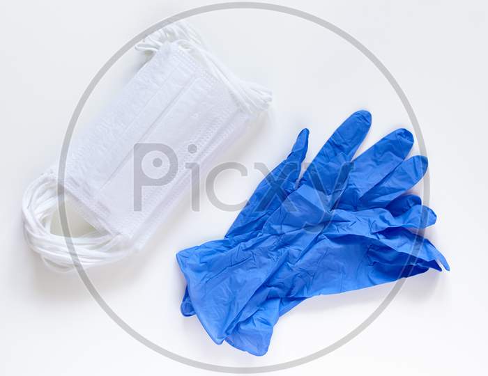 Pair Of Latex Medical Gloves And Surgical Ear-Loop Masks On White Background. Protection Concept. Coronavirus Covid-19 Pandemic.