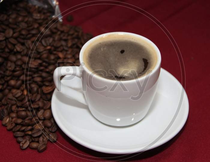 White Cup Of Coffee With Beans On Background Board