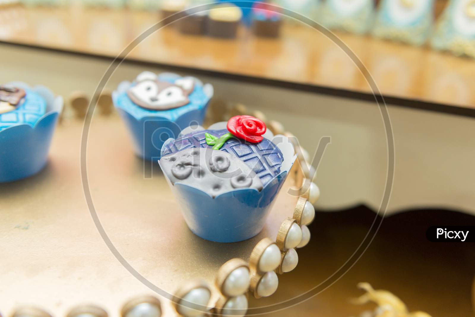 Closeup Of Decorated Chocolate Cupcakes In A Golden Tray Decorated By Pearls. Kids Birthday Party Decoration. Little Prince Theme Party. Selective Focus.