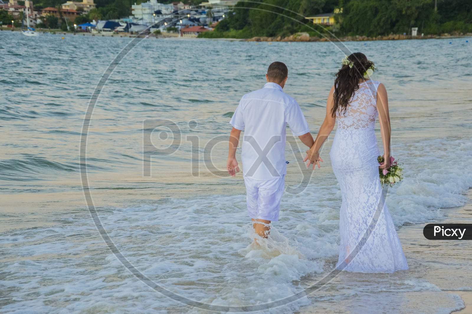 Beach Wedding With Bride And Groom Dressed In White.