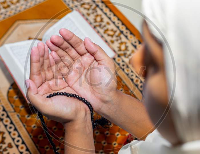 Muslim Asian Women Raise Their Hands To Pray On The Mat At Home. Indoors. Focus On Hands.