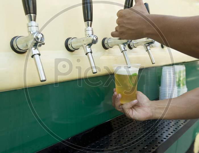 Bartender Pouring From Tap Fresh Beer Into The Plastic Cup.
