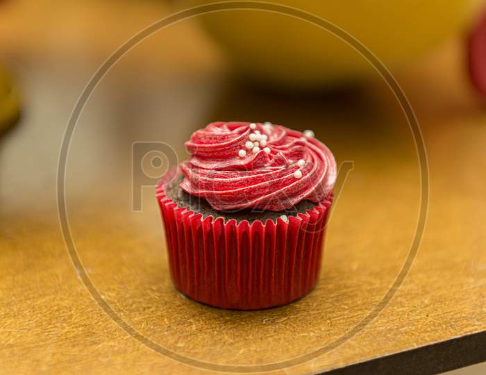 Delicious Chocolate Cupcake With Red Cream Icing And Sprinkles.