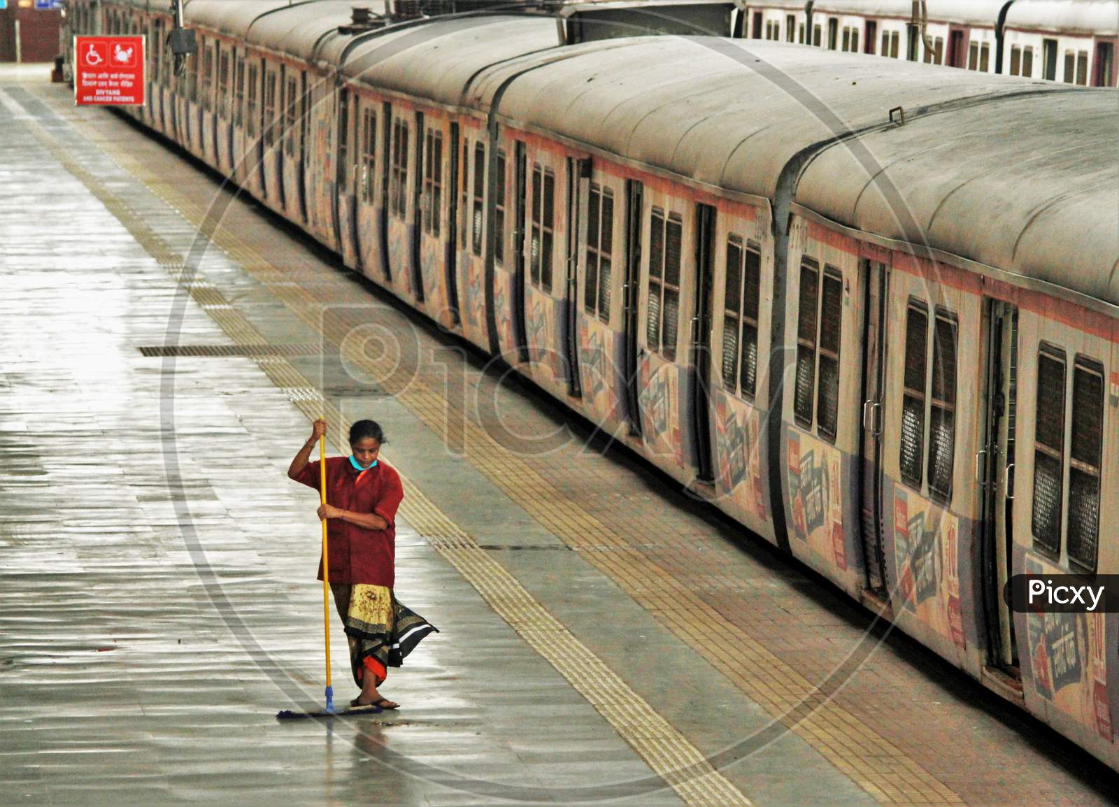 A railway worker sweeps the platform on the first day of local trains resuming for essential service workers after the government eased a nationwide lockdown which was imposed as a preventive measure against the COVID-19 coronavirus, at CST local train station, in Mumbai, India, on June 15, 202