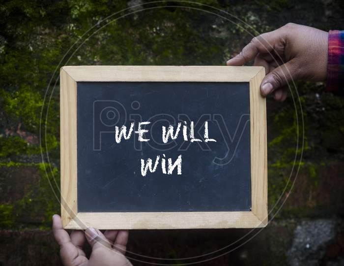A man holding a slate with comment "We will win" to give support for coronavirus