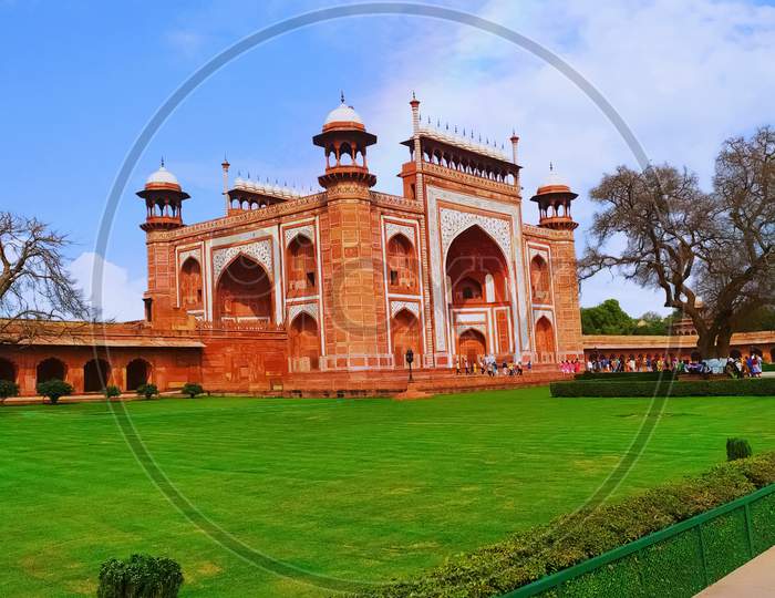 The great gate of Taj Mahal with green garden in Agra, India. famous buildings in the world sits is a red sandstone building known as Darwaza-i Rauza. it is a main entrance gate of Taj Mahal.