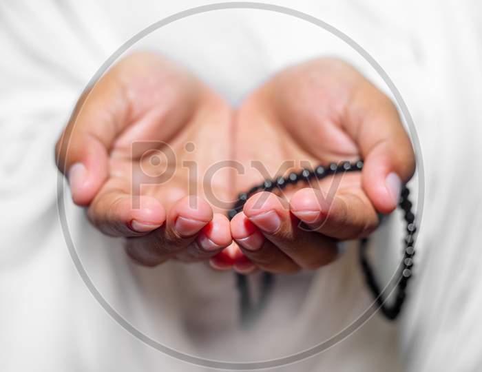 Muslim Women Raise Their Hands To Pray With A Tasbeeh On White Background, Indoors. Focus On Hands.