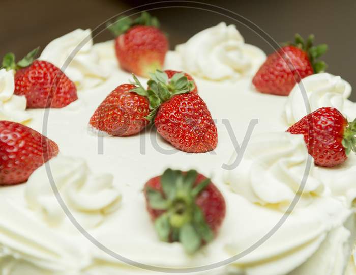 Close Up Of Creamy White Chocolate Cake With Strawberry Slices.