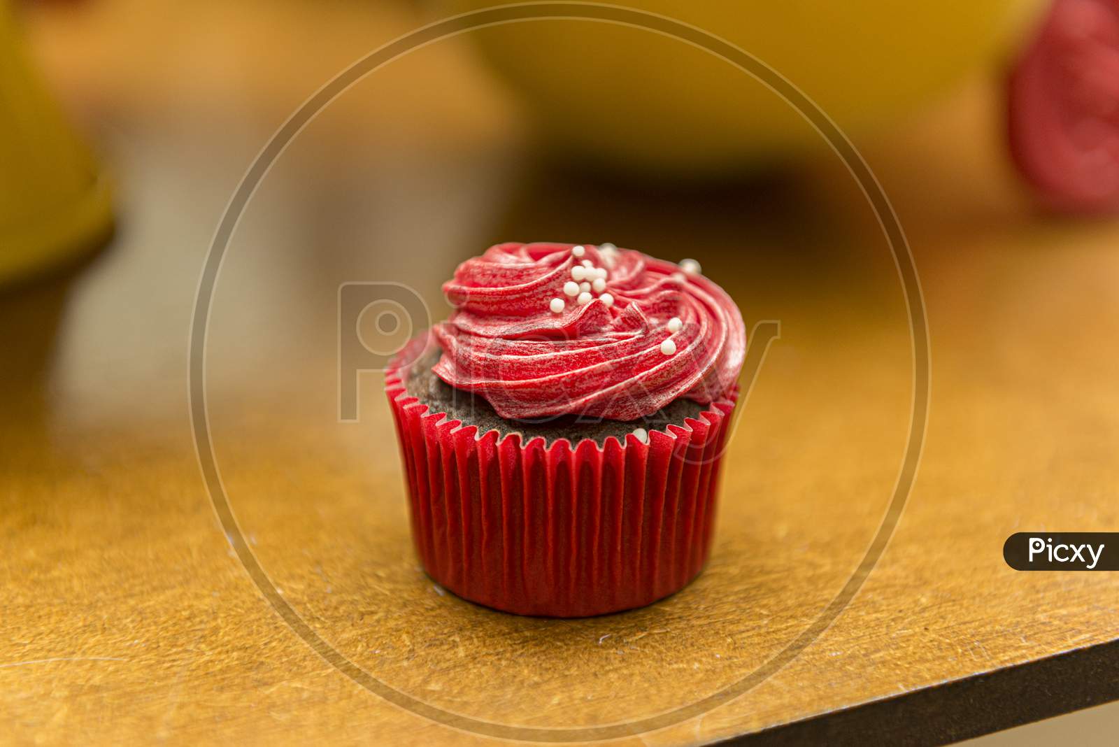 Delicious Chocolate Cupcake With Red Cream Icing And Sprinkles.