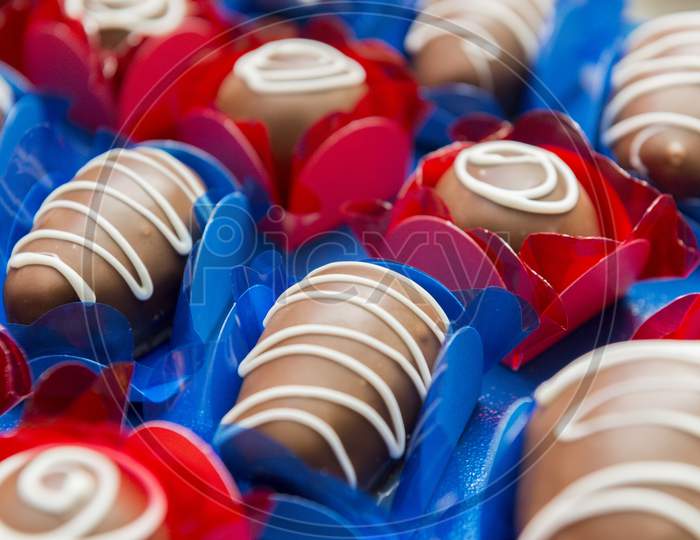Closeup Of Delicious Chocolate Candies. Different Type Of Chocolate Candies On A Blue And Red Background - Top View.