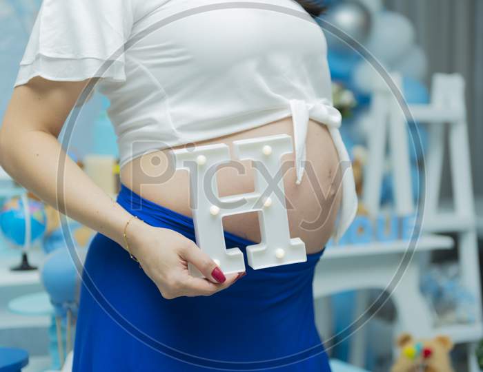 Close-Up Of Torso Of Young Pregnant Model Standing In Baby Shower.