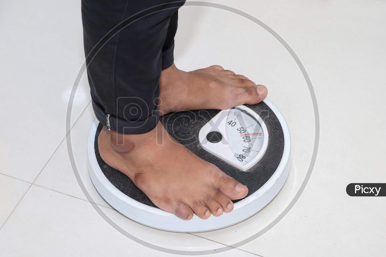 Low Section Of Man Standing On Weighing Scale