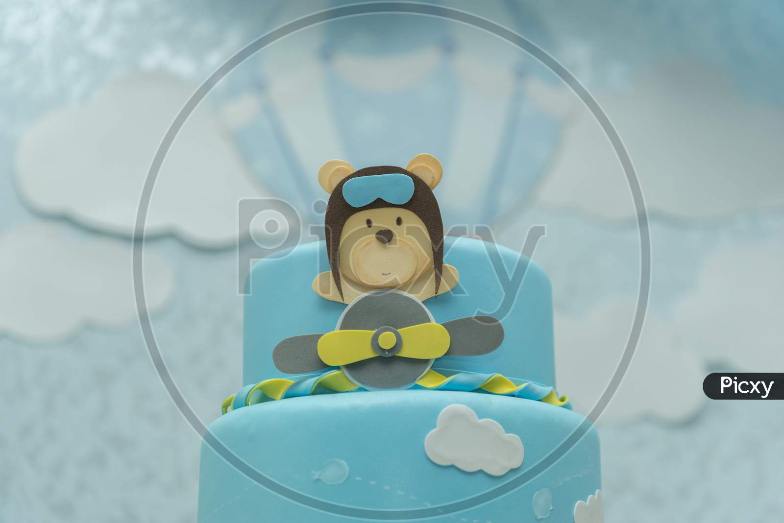 Close Up Of Blue Cake Decorated With Cute Aviator Bear, Plane And Clouds.