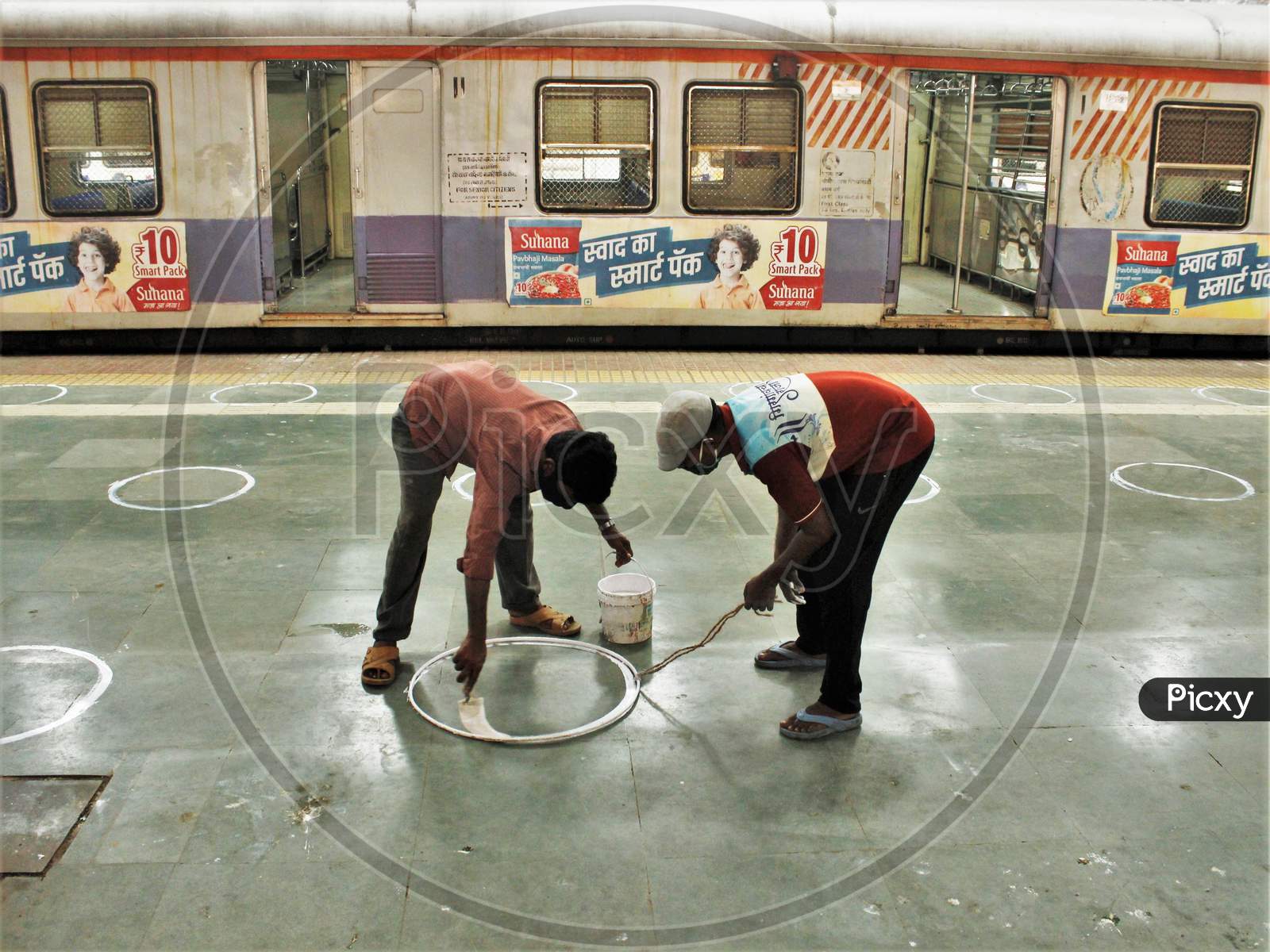 Workers paint circles on the platform for the passengers to maintain social distancing after the government eased a nationwide lockdown which was imposed as a preventive measure against the COVID-19 coronavirus, at the CST local train station, in Mumbai, India, on June 15, 2020.