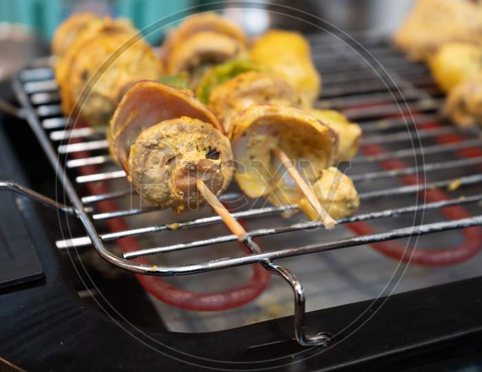 Wooden Skewer With Vegetables Like Mushroom, Chilli Pepper, Green Pepper Onions And Potatoes Cooking On An Electric Grill