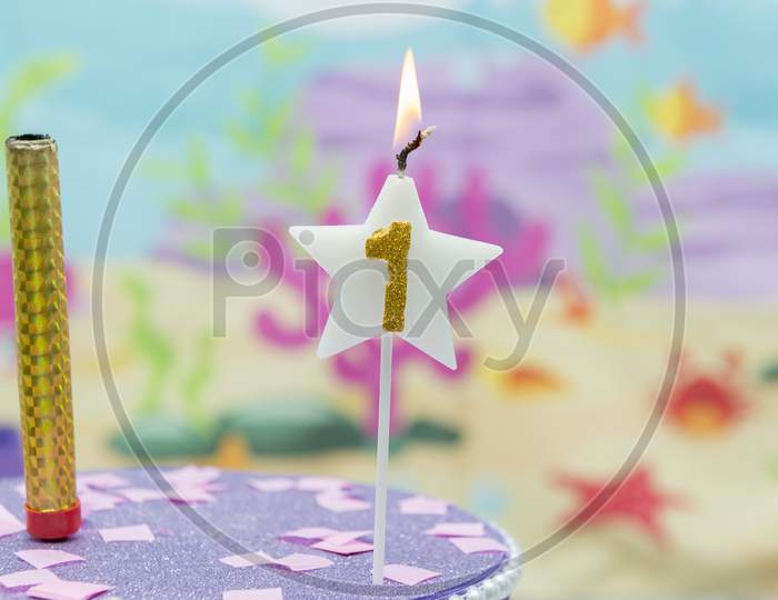 Lighted Birthday Candle In Star Shape With Blurred Background. 1 Year Anniversary, Deep Sea Theme. Celebration, Party And Joy Concept.