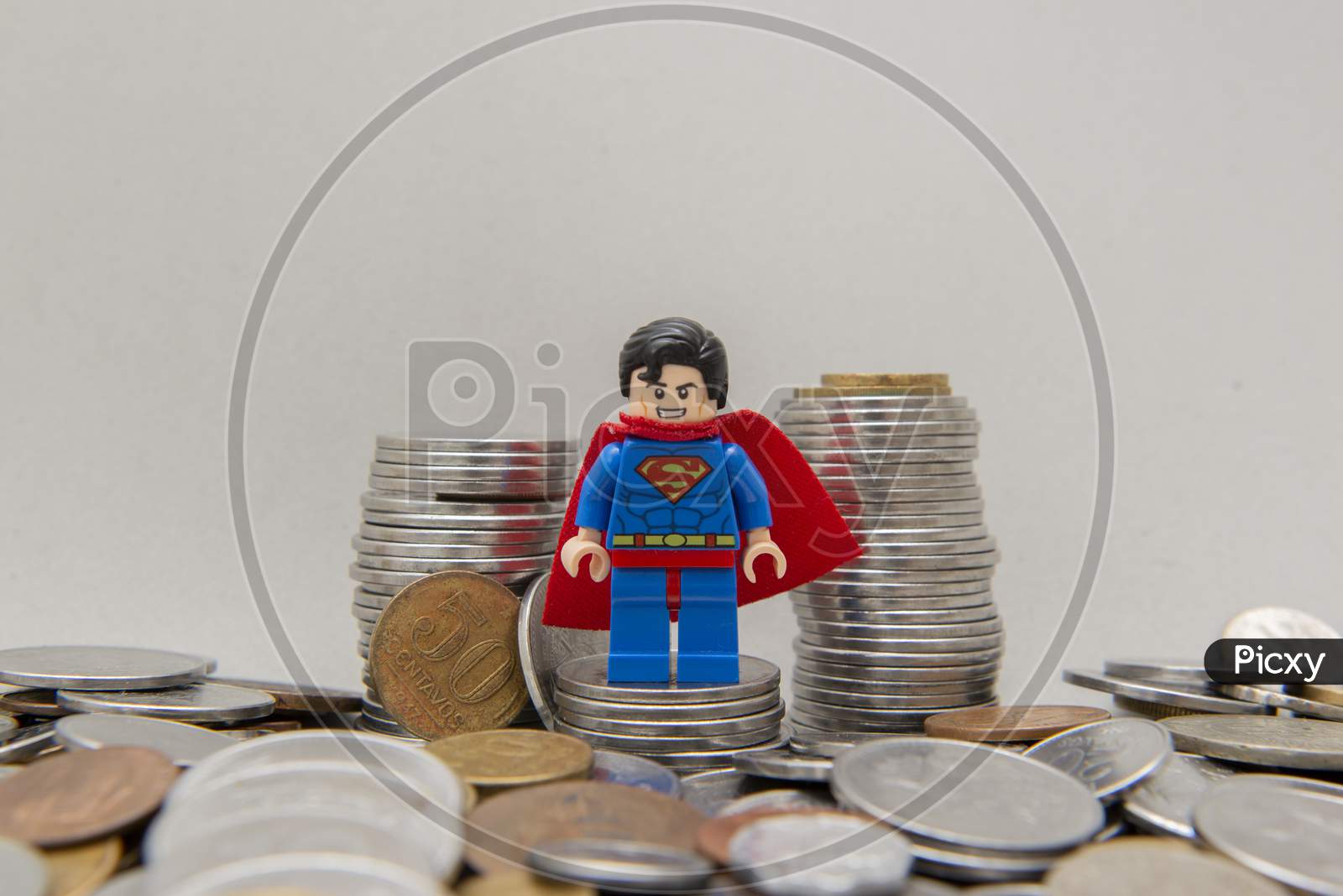 Superman On A Pile Of Silver Coins On White Background
