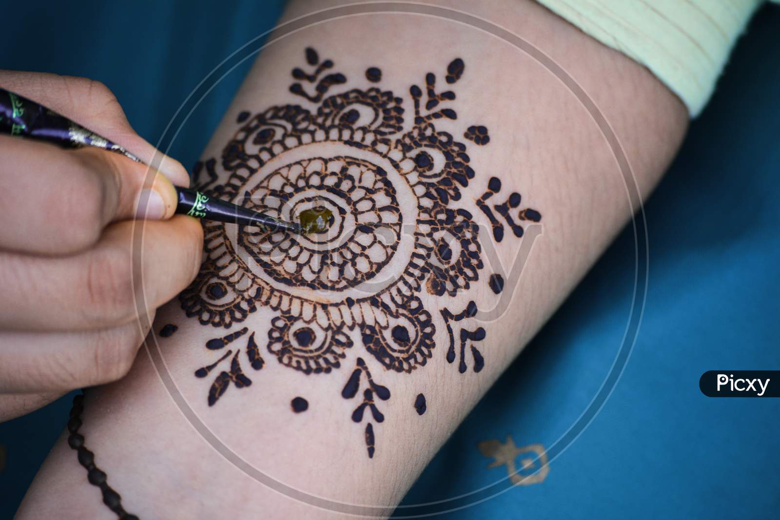 Mehndi Artist making mehndi design on the Indian bridal hand. Mehndi is traditional Indian decorative art.