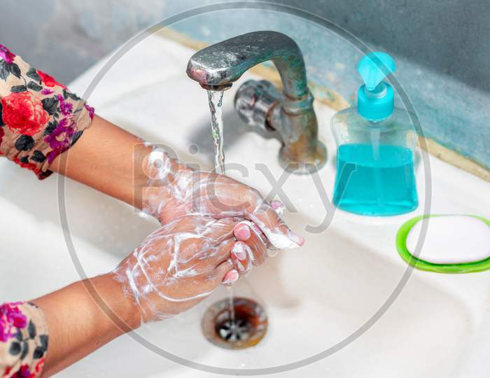 Women Use Liquid Soap For Rubbing And Washing Her Hands Under The Water Tap. Hygiene Concept. Wash Hands To Stop Spreading Coronavirus.