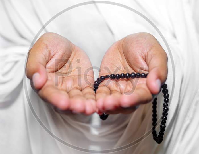 Muslim Women Raise Their Hands To Pray With A Tasbeeh On White Background, Indoors. Focus On Hands.