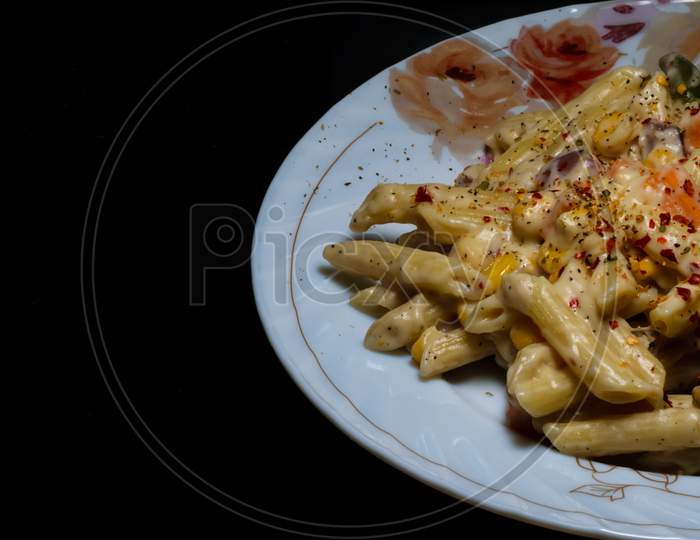 Pasta With White Sauce And Cheese Placed In A Plate In A Dark Background