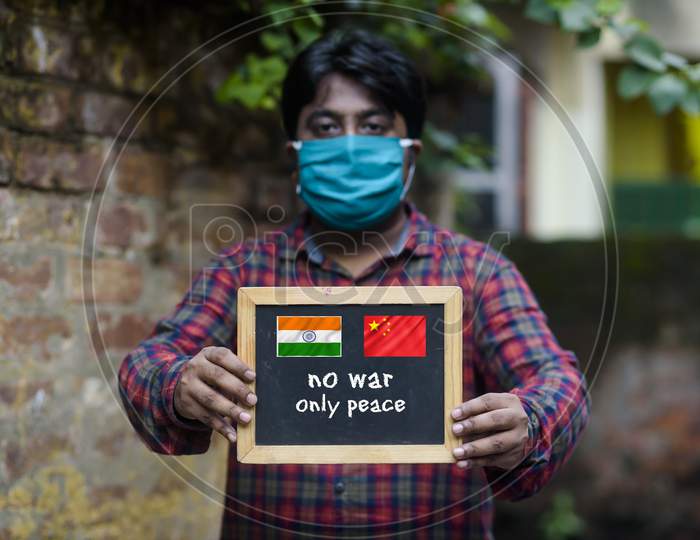 A man holding a black slate with comment "NO WAR ONLY PEACE" to support peace process for the recent China's attack to India