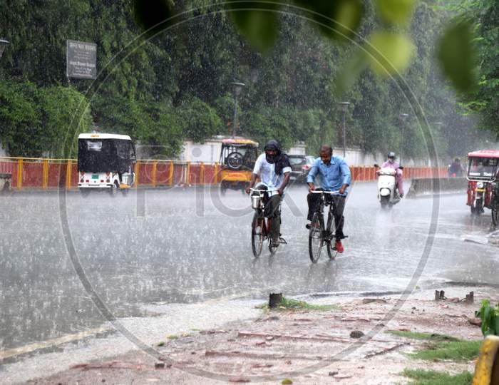 Men pedal their bicycles On The Road During a Heavy Pre Monsoon Rain In Prayagraj, June 17, 2020.