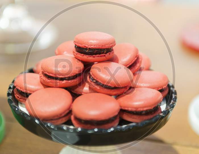 Several Red Macaroons On A Black Ceramic Tray.
